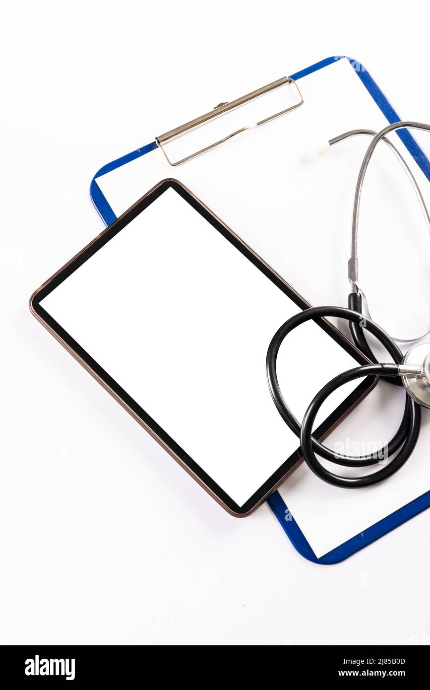 High angle view of digital tablet with stethoscope and clipboard on ...