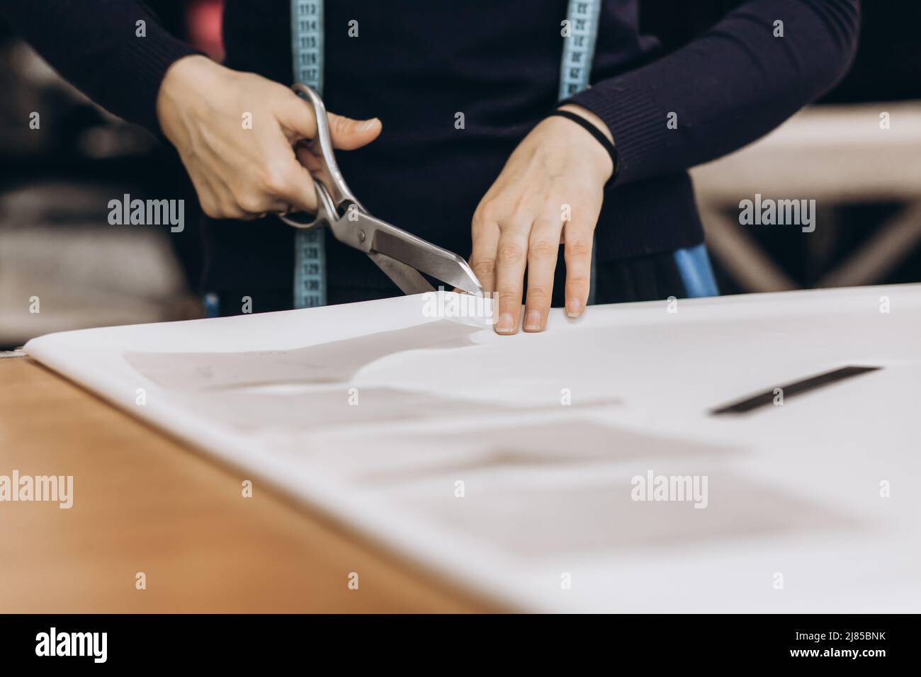 The tailor cuts out the fabric according to the pattern, close up. Profession of tailor and cutter, small business Stock Photo