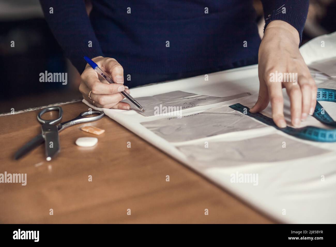 Tailor sews clothes. A woman dressmaker makes patterns in her atelier