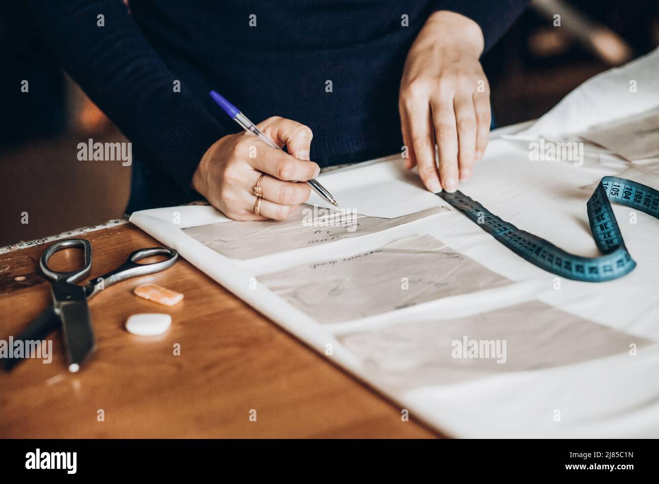 Tailor sews clothes. A woman dressmaker makes patterns in her atelier ...