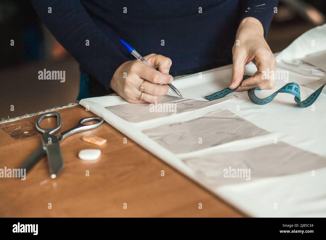 Tailor sews clothes. A woman dressmaker makes patterns in her atelier ...