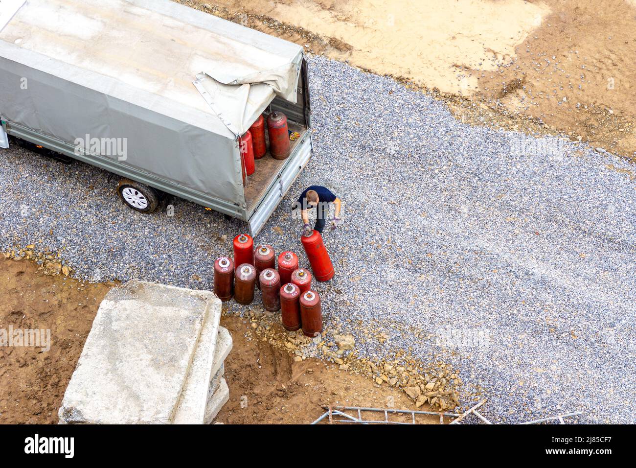 A man loads red gas cylinders into the body of a truck under an awning, selective focus Stock Photo