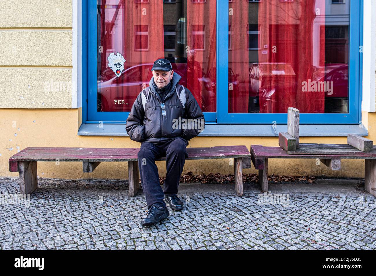 Senior male sitting on bench outside Perlin Wine Bar Exterior in Griebenowstrasse, Mitte, Berlin Stock Photo