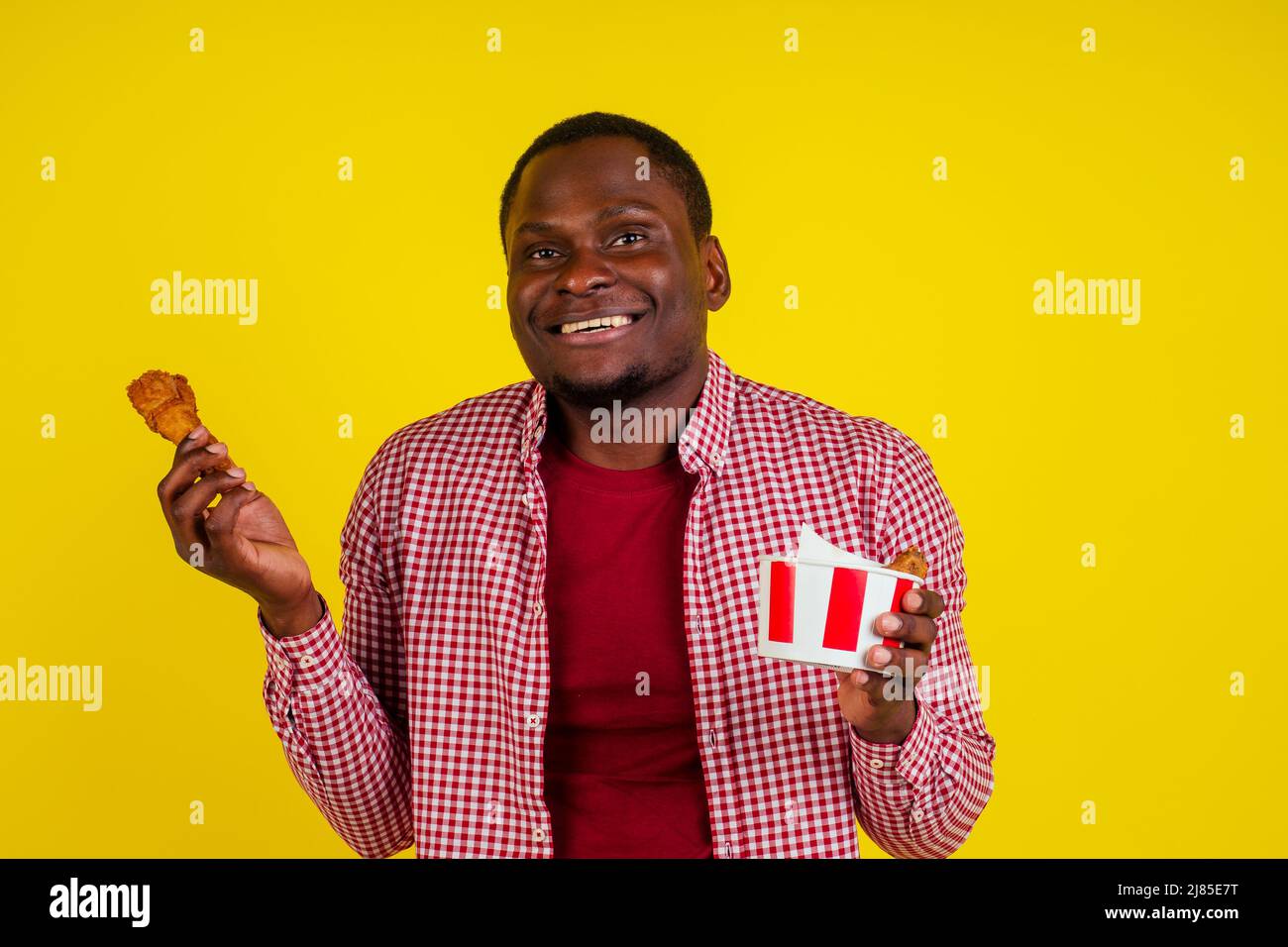 funny african american man eating fried chicken leg in studio yellow  background Stock Photo - Alamy, image size:1300x956