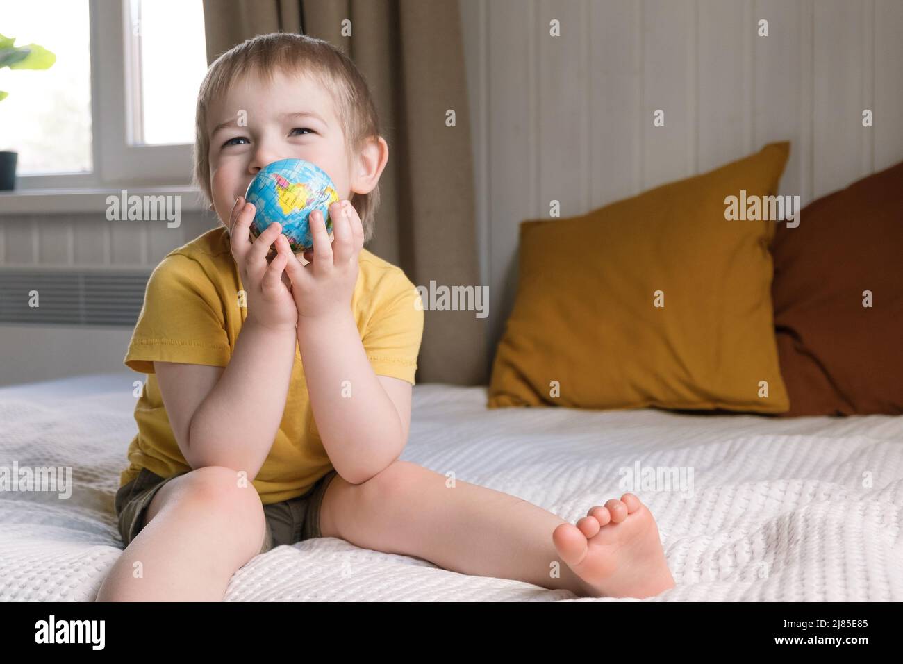 Child boy with blonde hair hugging earth globe, save earth concept. 3 years old kid holding globe model. Baby toddler. Children education development Stock Photo