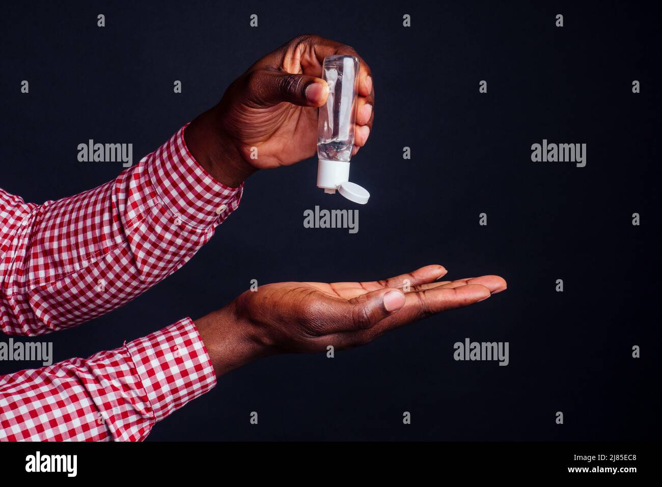 close up hands of afro male useing antiseptic in studio black background.washing hands before eating concept Stock Photo