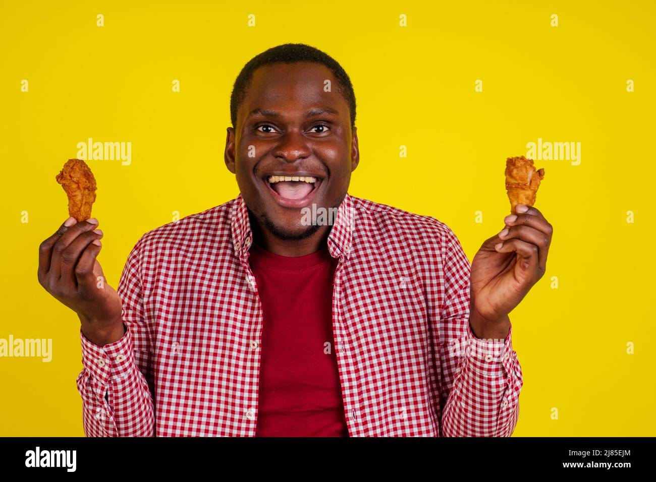 funny african american man eating fried chicken leg in studio yellow  background Stock Photo - Alamy, image size:1300x956