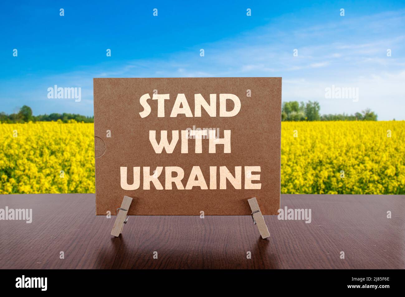 Stand with Ukraine text on card on the table with mountains background. Stock Photo