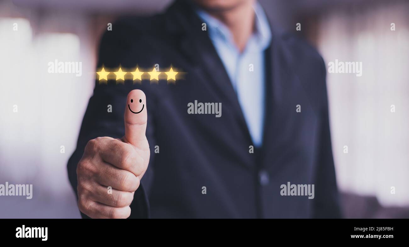 Customer satisfaction concept. Hand with thumb up Positive emotion smiley face icon and five star with copy space. Stock Photo