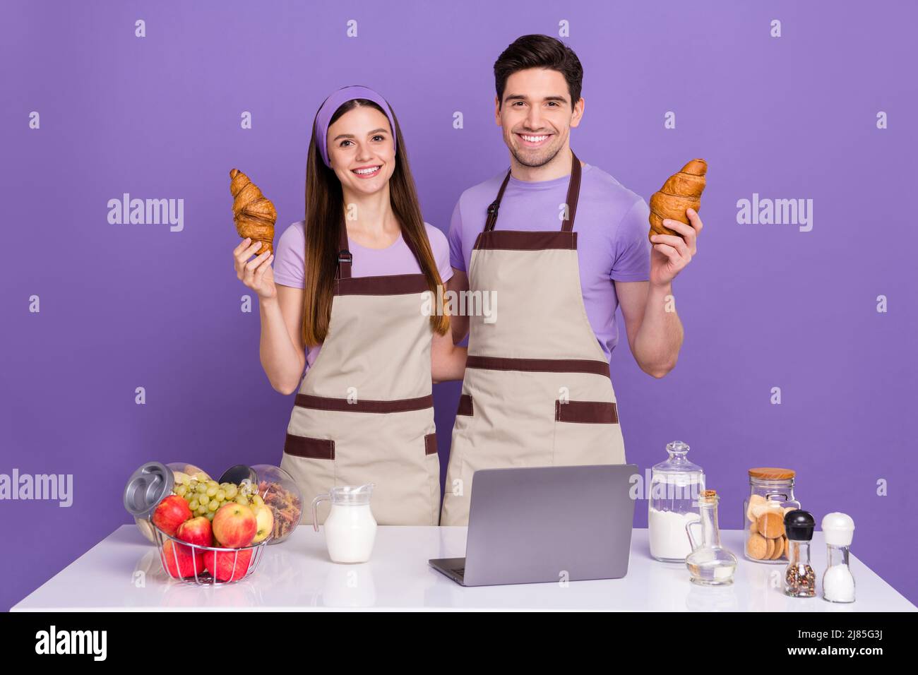 Photo of pretty sweet boyfriend girlfriend dressed chef outfits cooked tasty pastry gadget isolated purple color background Stock Photo
