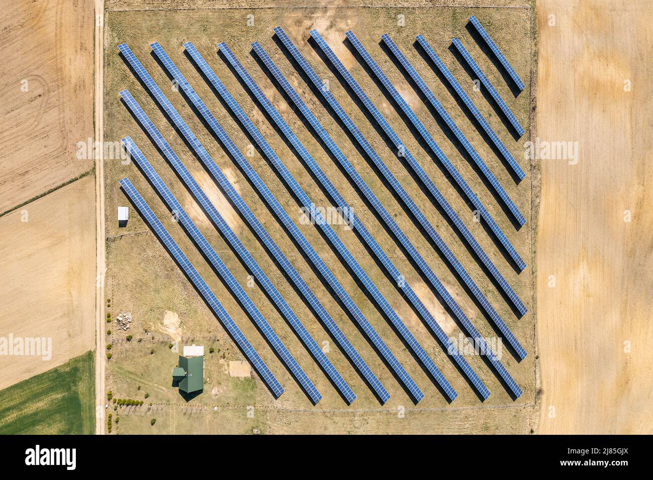 Solar farm aerial view, rows of PV panels by a small house Stock Photo