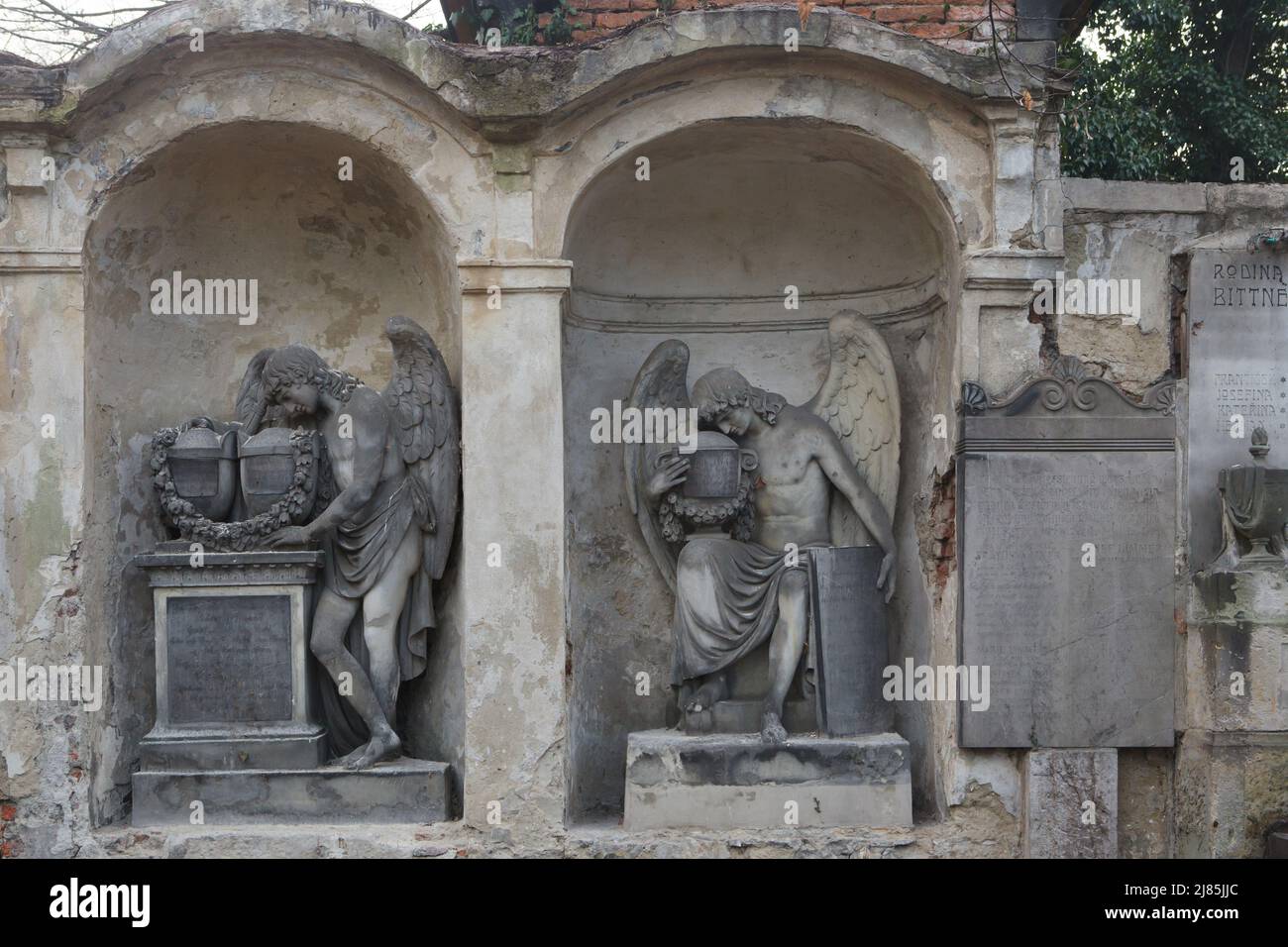 Mourning angels depicted on abandoned funeral monuments at Olšany Cemetery in Prague, Czech Republic. Stock Photo