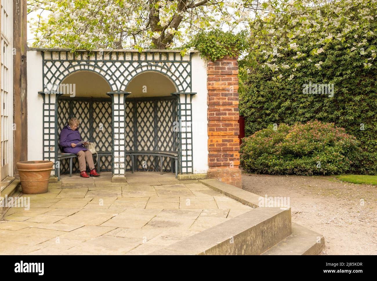 Knutsford Cheshire-united kingdom April 24 2022 Caucasian lady sitting resting reading a magazine on a garden patio Stock Photo