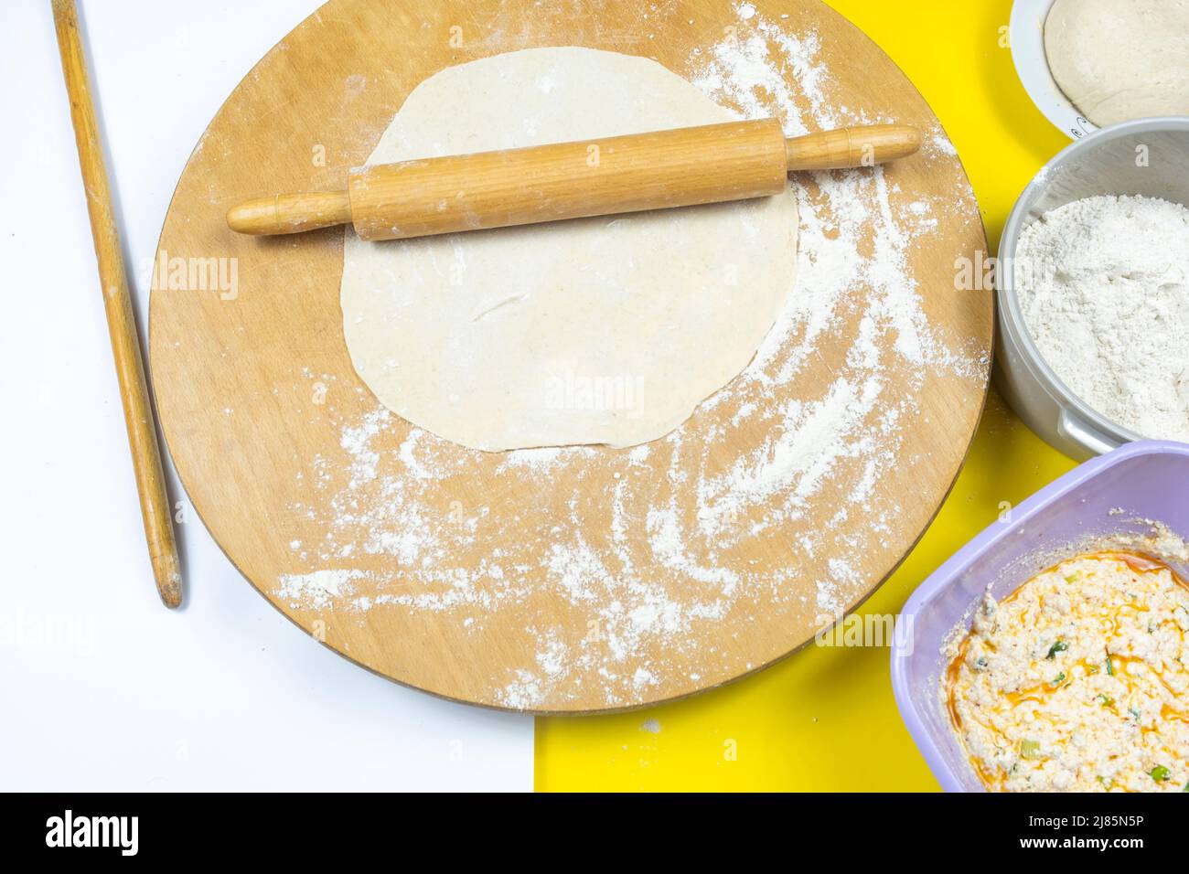 Rolling pins and traditional circle wooden board, ingredients in the plate, cooking concept, top view of roller and some flour, making homemade meal Stock Photo