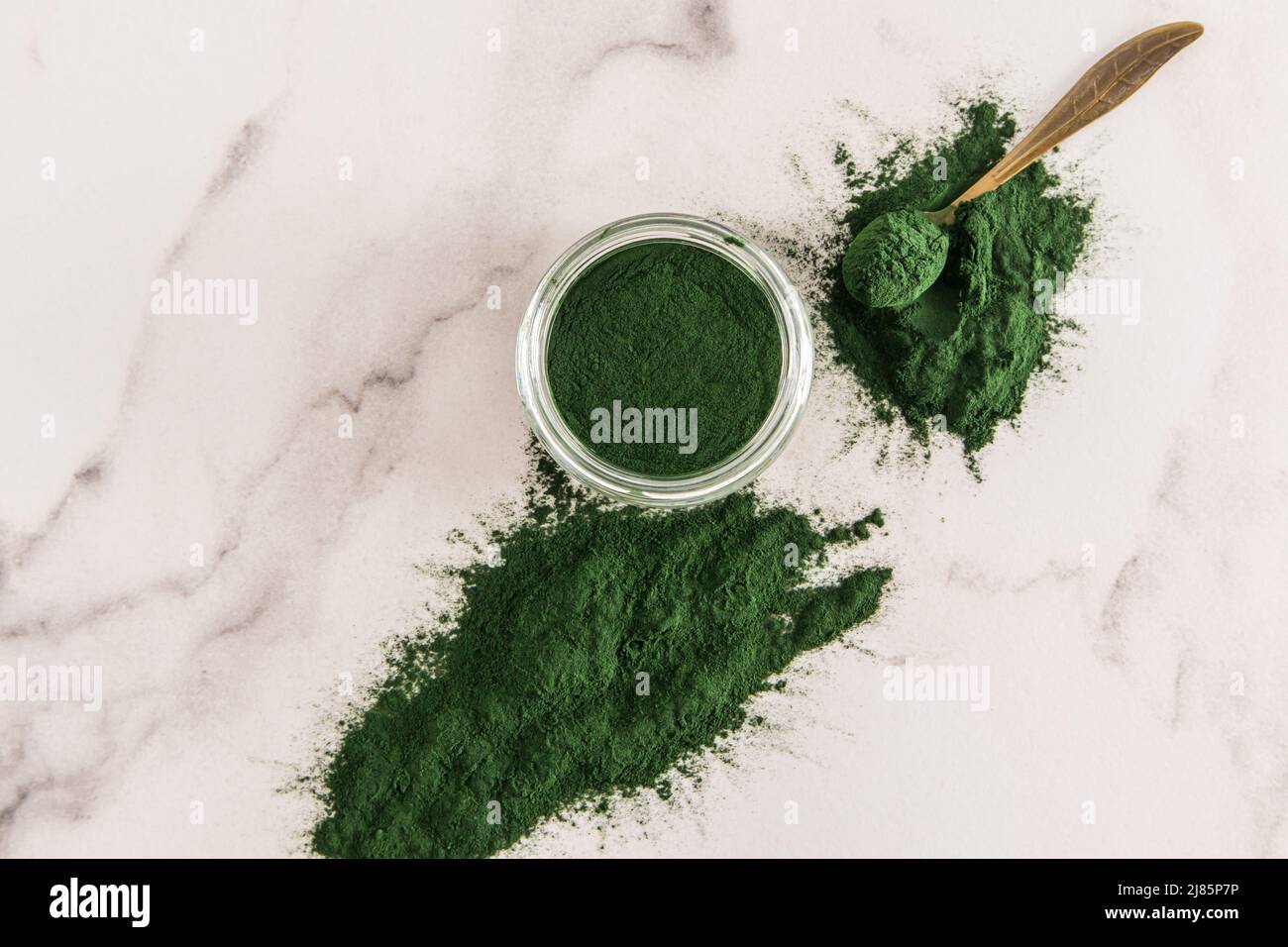 a glass jar filled with organic powder of green spirulina algae on a ...