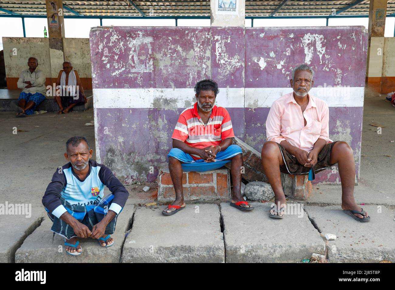 Three fishermen resting at the fish market in Tangassery, Thangassery, Kerala, India.        market men outside raw real people sea shrimp street trad Stock Photo