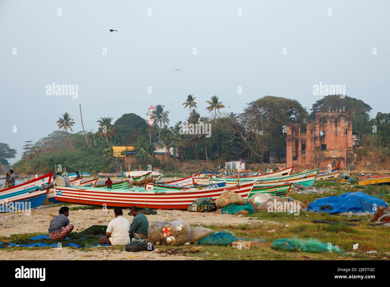 Group of  fishermen sitting on the beach mending their fishing nets,Tangassery, Kerala, India. Stock Photo