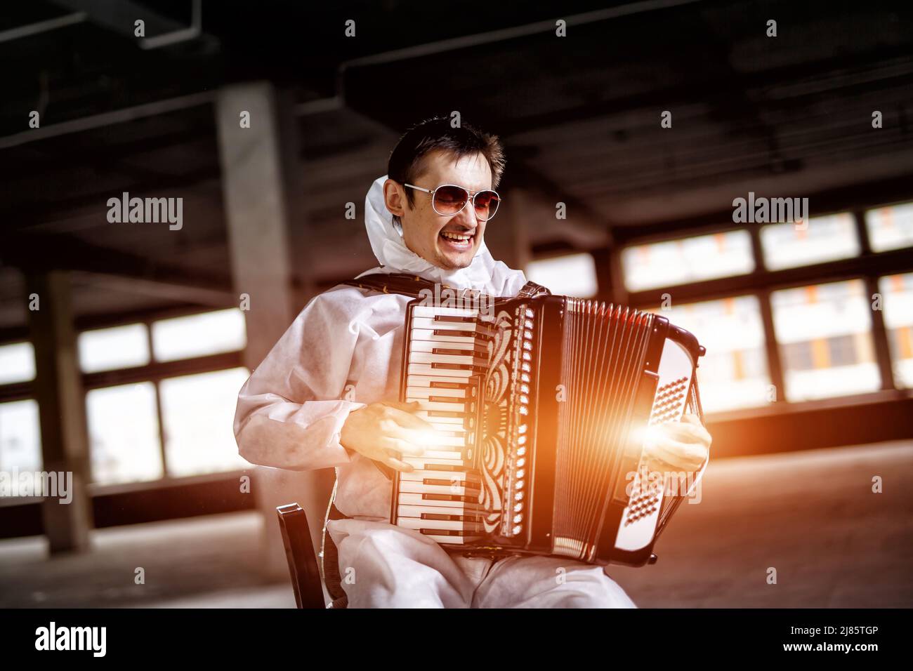 The musician playing the harmonica, accordion in the hall with columns