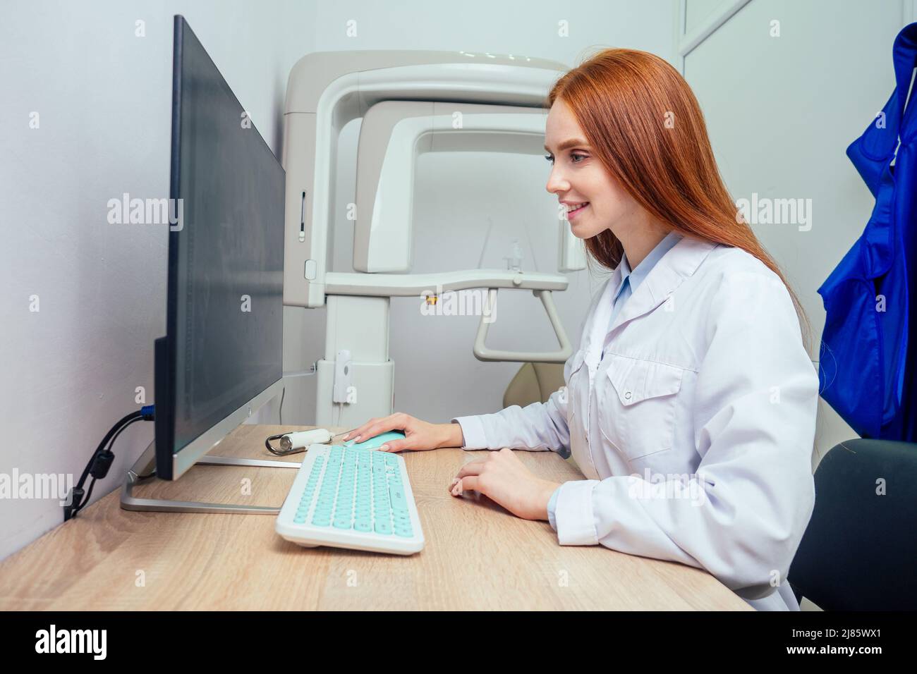 redhaired ginger female dentist showing mouth xray on computer Stock
