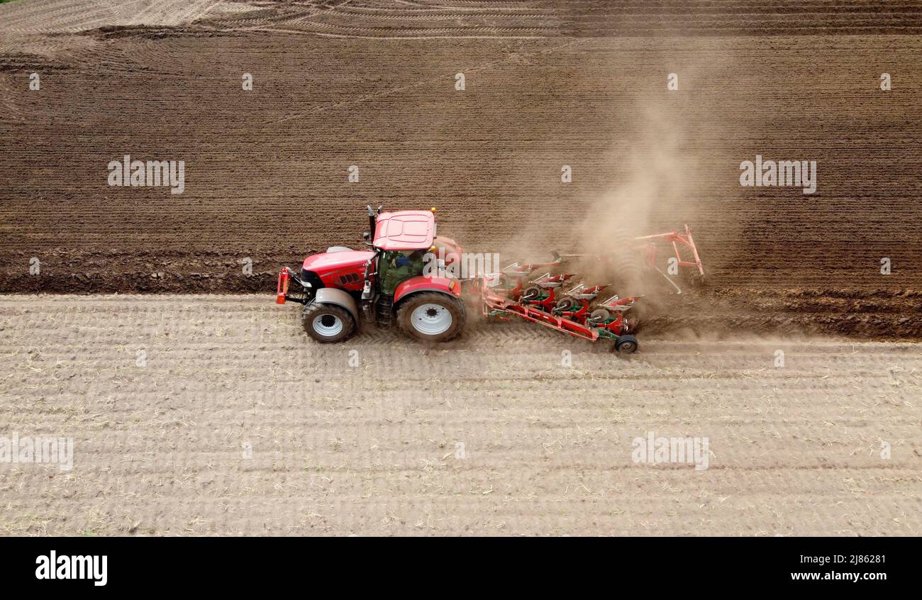 A farmer is plowing his dry farmland in the spring. Stock Photo