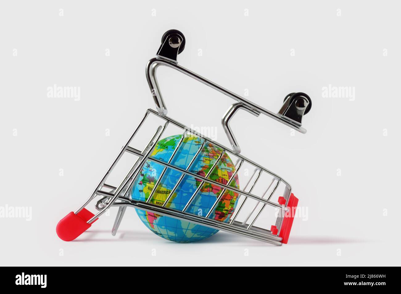 Earth globe imprisoned in an inverted shopping cart on white background - Concept of shopping and global market Stock Photo