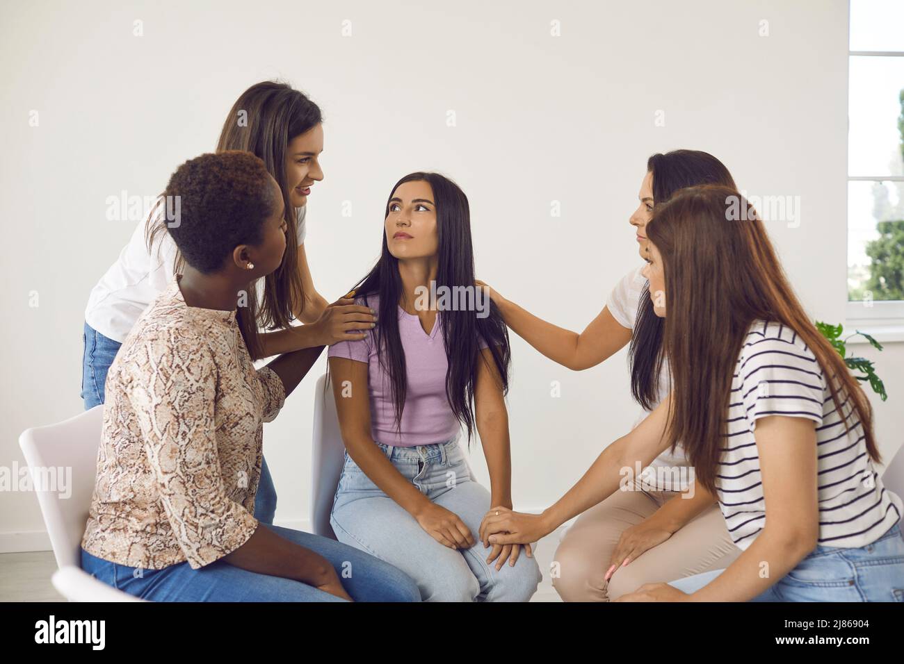 Diverse group of women talking to young friend, supporting her, giving her advice Stock Photo