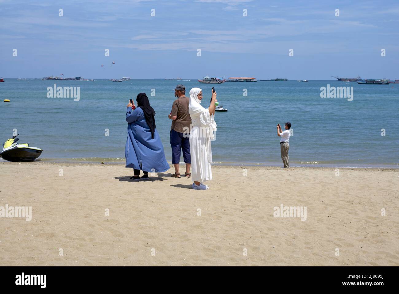 Arab selfie. Arab women in traditional abaya clothing taking selfies on the beach. Pattaya Thailand Stock Photo