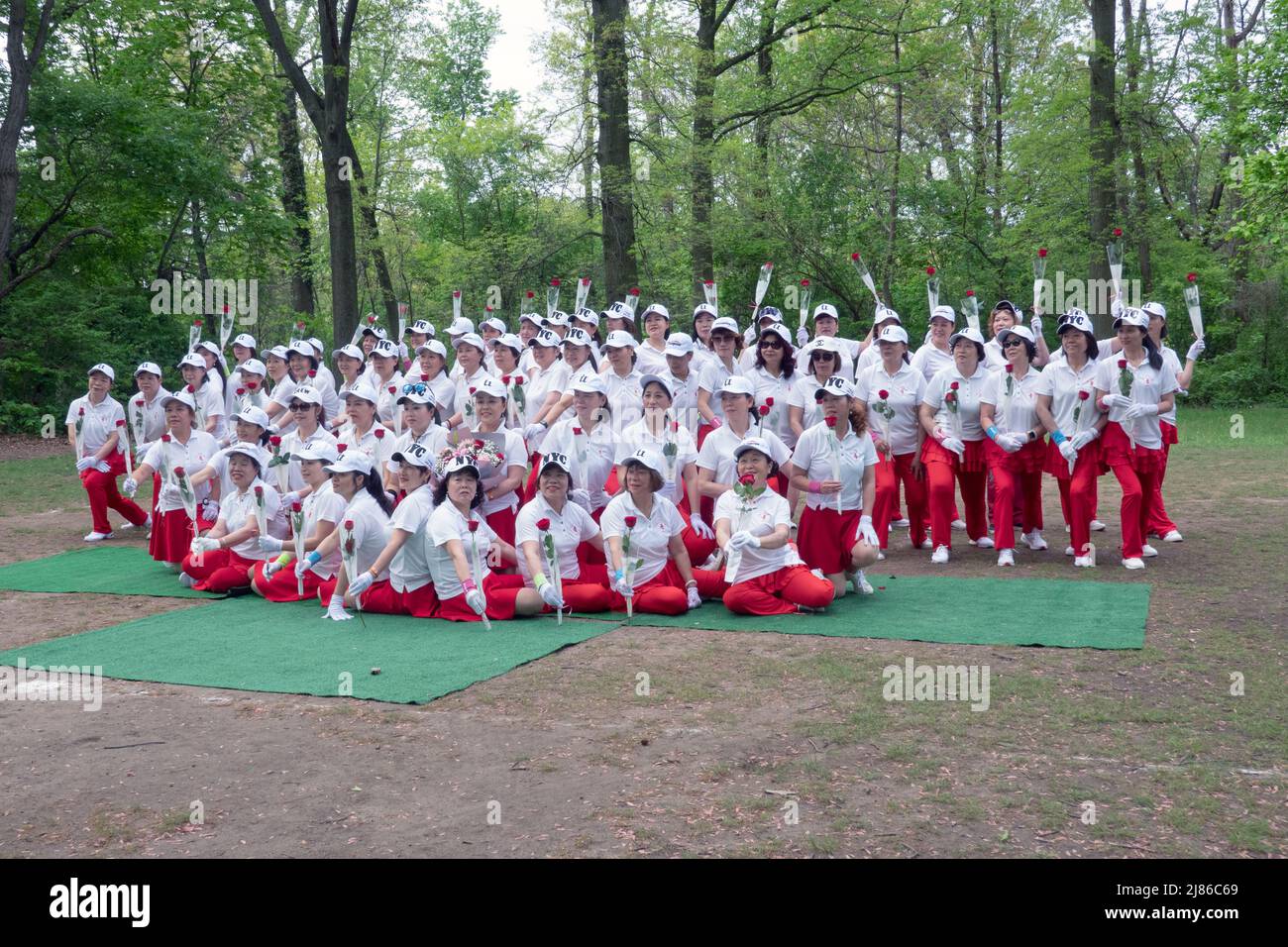 Women from Wenzhou, China in the Kai Xin Yizhu dance troupe celebrate Mother's Day by posing for a group photo while holding roses. In a park in NYC. Stock Photo