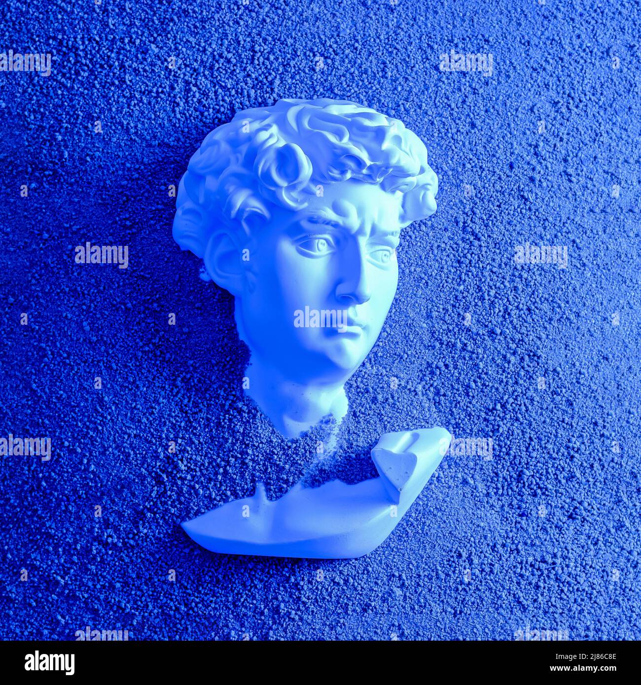 Bust head of David plaster antique in the sand on the beach. Minimal concept of futurism, cyberpunk and vaporway. Stock Photo