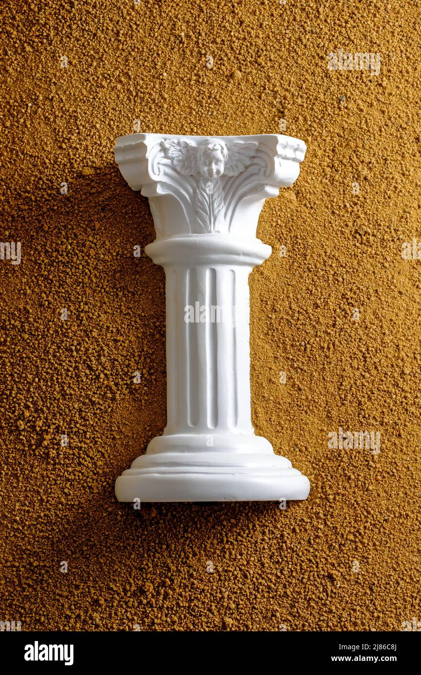 White antique column in yellow sand. Creative minimal history and archeology concept. Stock Photo