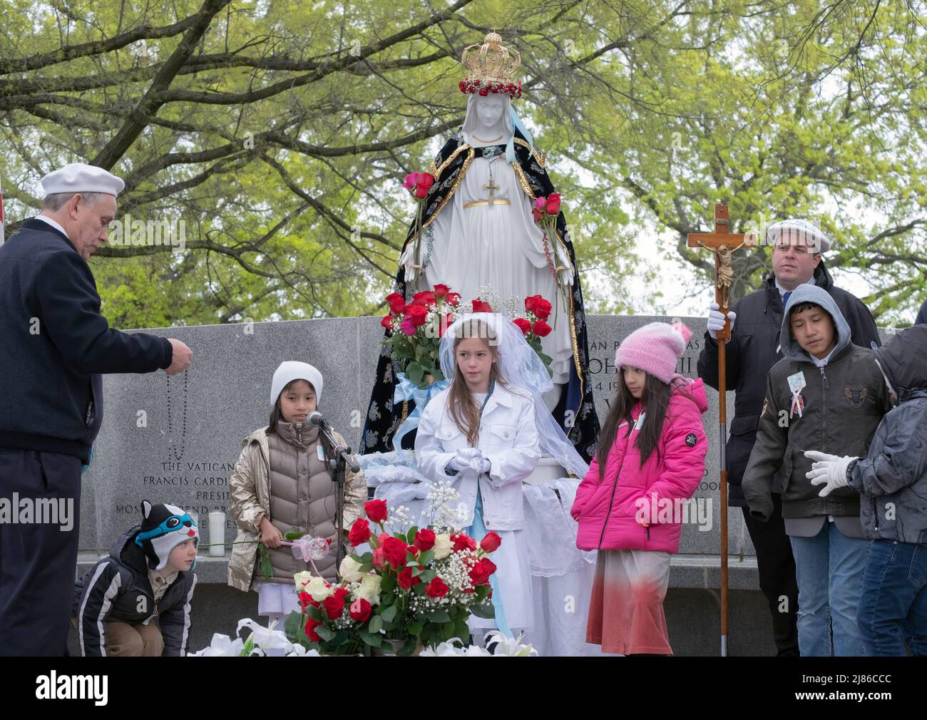 Adults & children  worship at the May Crowning event in Flushing Meadows Corona Park at the site of the Vatican Pavilion from the 1964 World's Fair. Stock Photo