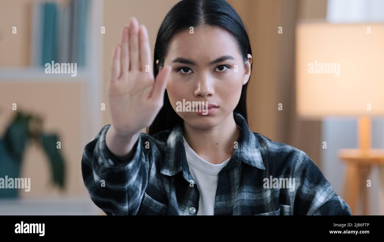 Portrait serious frustrated angry girl korean japanese chinese woman looking at camera holding hand in front forbidden gesture refusal keep distance Stock Photo