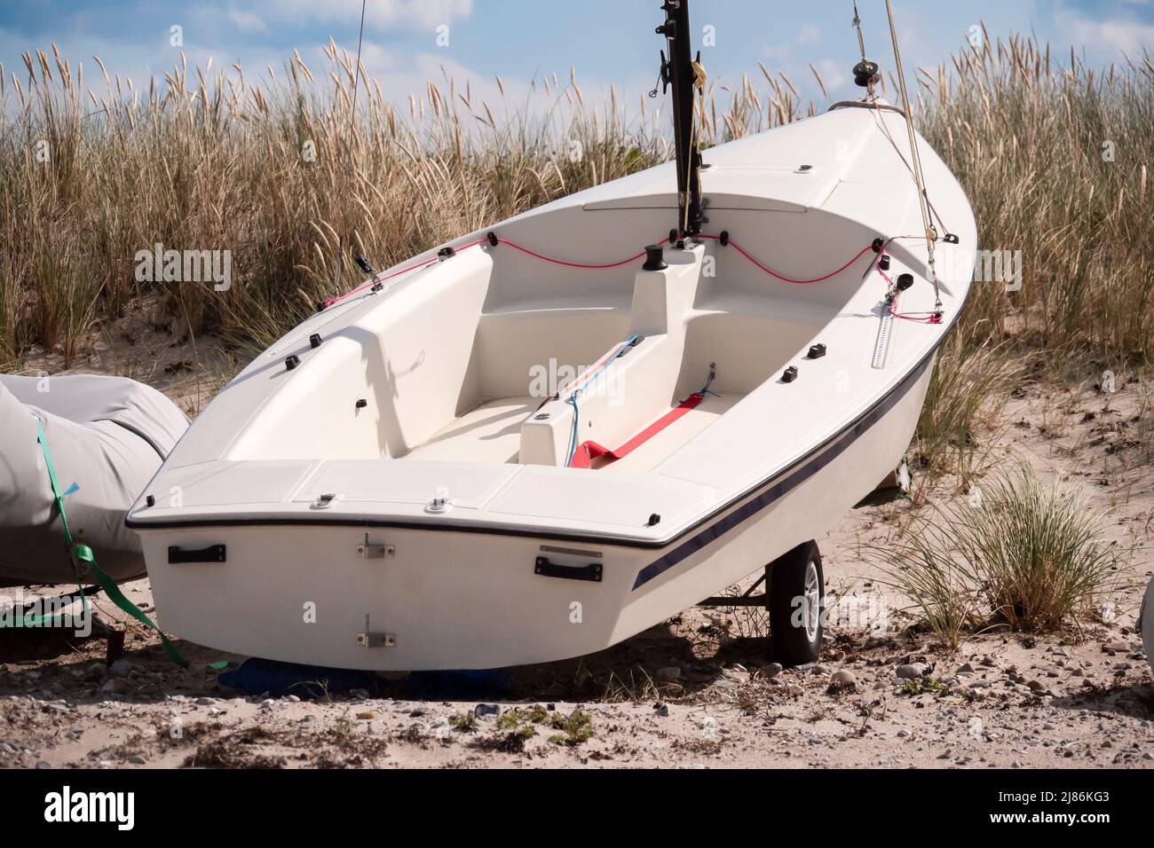 A small sailboat on the trailer on the sandy beach with dune grass Stock Photo