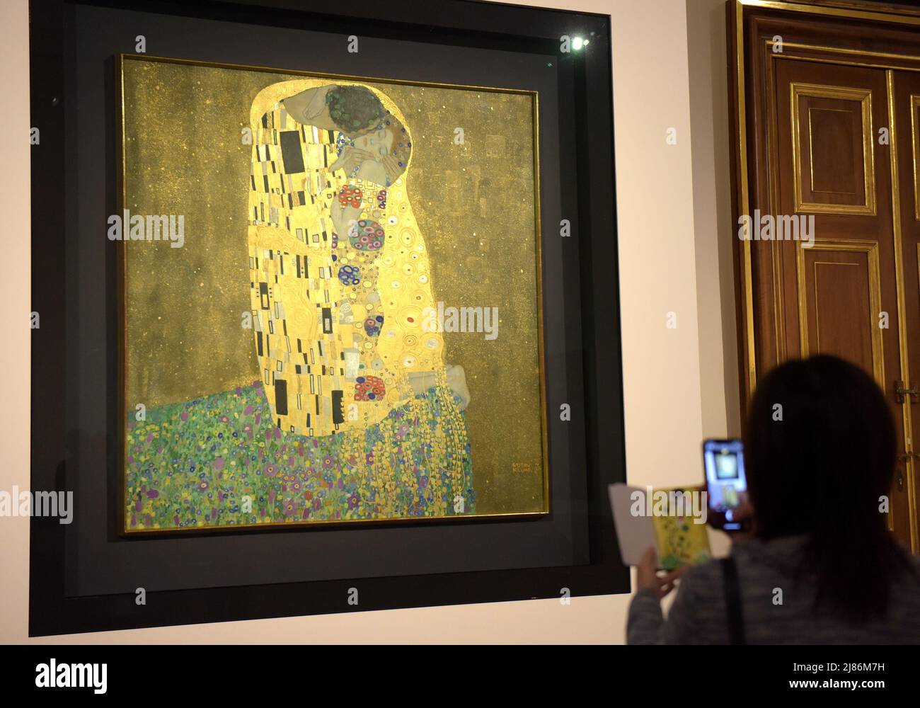 Vienna, Austria. 12th May, 2022. A visitor views 'The Kiss' by Gustav Klimt at the Upper Belvedere in Vienna, Austria, May 12, 2022. The Upper Belvedere in Vienna houses one of Austria's most valuable art collections - with key works by Gustav Klimt, Egon Schiele and Oskar Kokoschka. The heart of the Belvedere collection is formed by the 24 paintings of Gustav Klimt with his golden images 'The Kiss' and 'Judith'. 'The Kiss' in particular is world-famous. Credit: Guo Chen/Xinhua/Alamy Live News Stock Photo