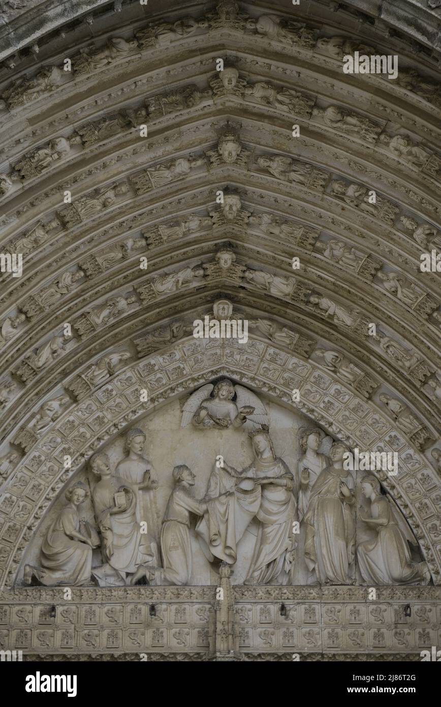 Spain, Castile-La Mancha, Toledo. Cathedral of Saint Mary. Built in Gothic style between 1227 and 1493. Main facade. Gate of Forgiveness. Built under the direction of the architect Alvar Martínez (active between 1418 and 1440). Tympanum. Sculptural relief representing the Virgin imposing the chasuble on Saint Ildephonsus (607-667). Stock Photo