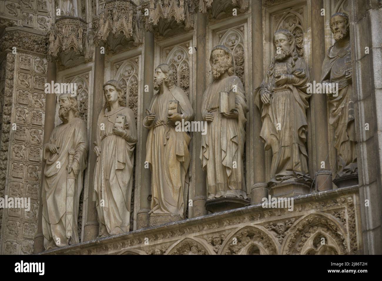 Spain, Castile-La Mancha, Toledo. Cathedral of Saint Mary. Built in Gothic style between 1227 and 1493. Main facade. Gate of Forgiveness. Built under the direction of the architect Alvar Martínez (active between 1418 and 1440). Detail of the sculptures of the apostolate in the jambs. Stock Photo