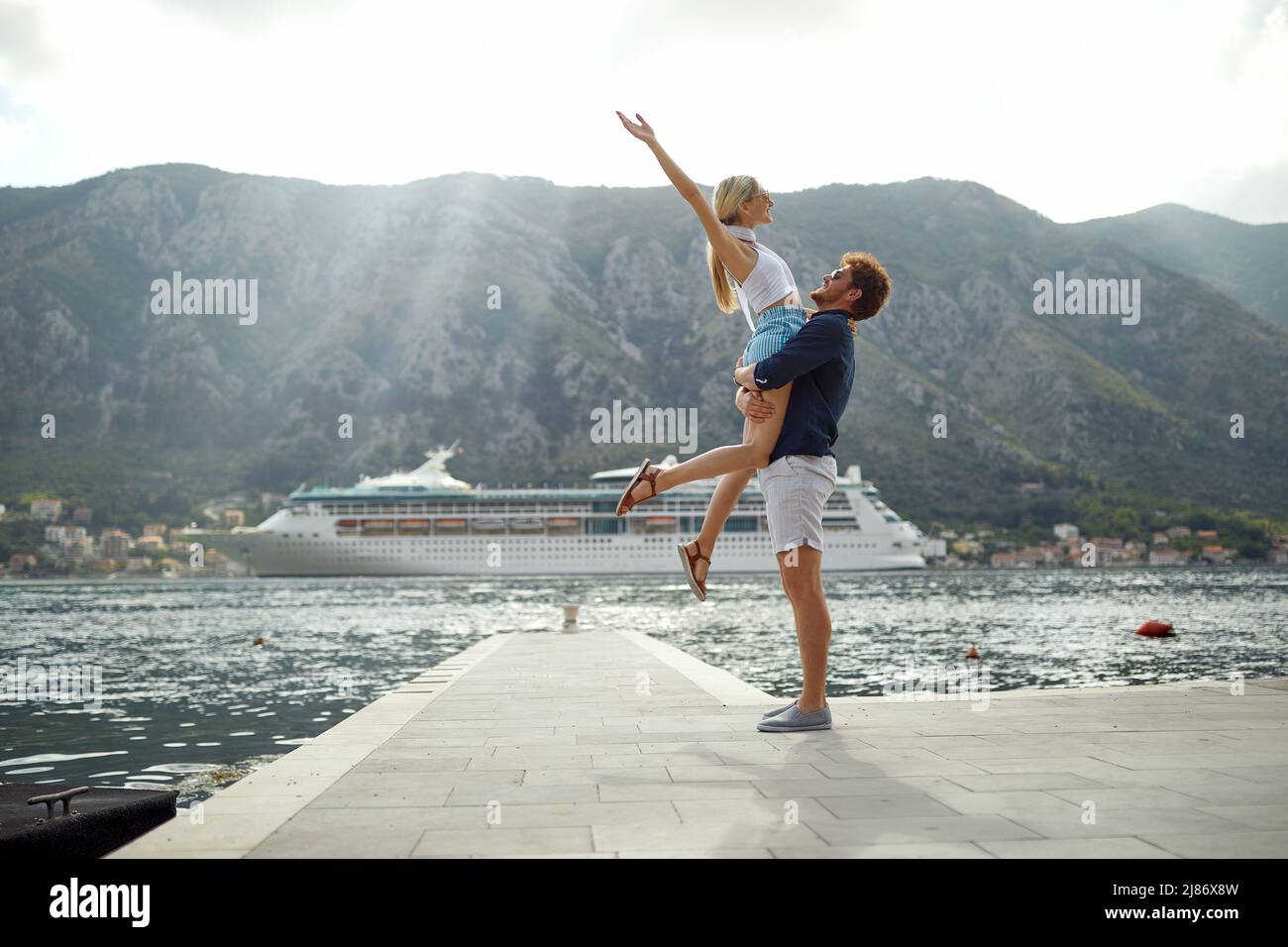 Summer love. Happy couple on dock. Man holding woman, she is enjoying freedom. Travel, love, fun, togetherness concept. Stock Photo