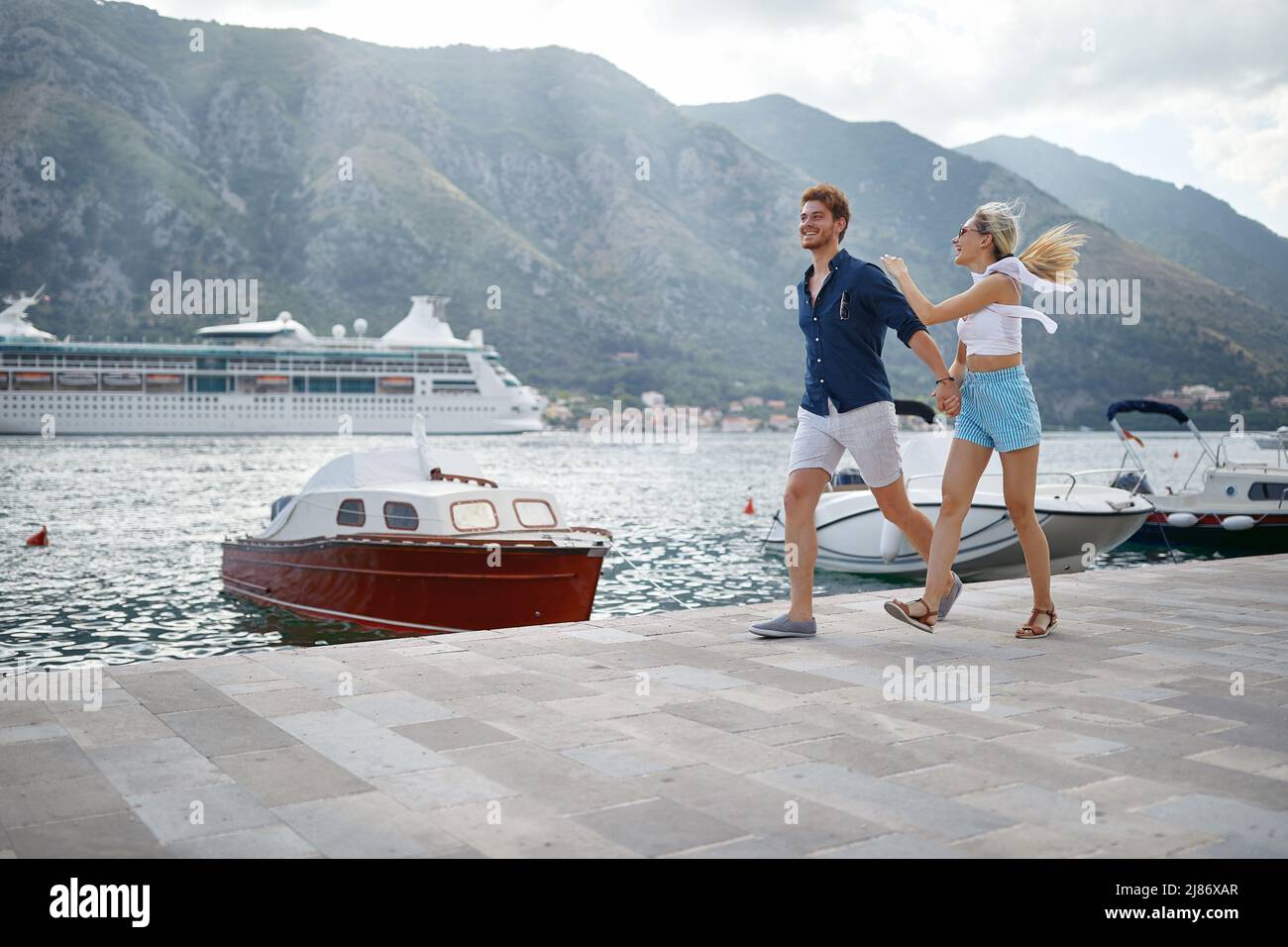 Summer love. Happy couple on dock holding hands and jumping. Travel, love, fun, togetherness, lifestyle concept. Stock Photo