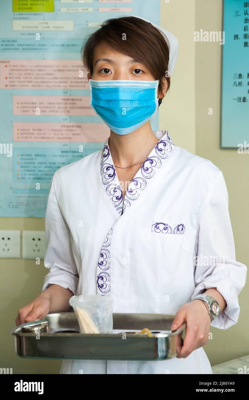 Nurse female medical staff, woman, in uniform and wearing surgical face mask to reduce infection spread, at a modern hospital in Xian, China. PRC. China. (125) Stock Photo