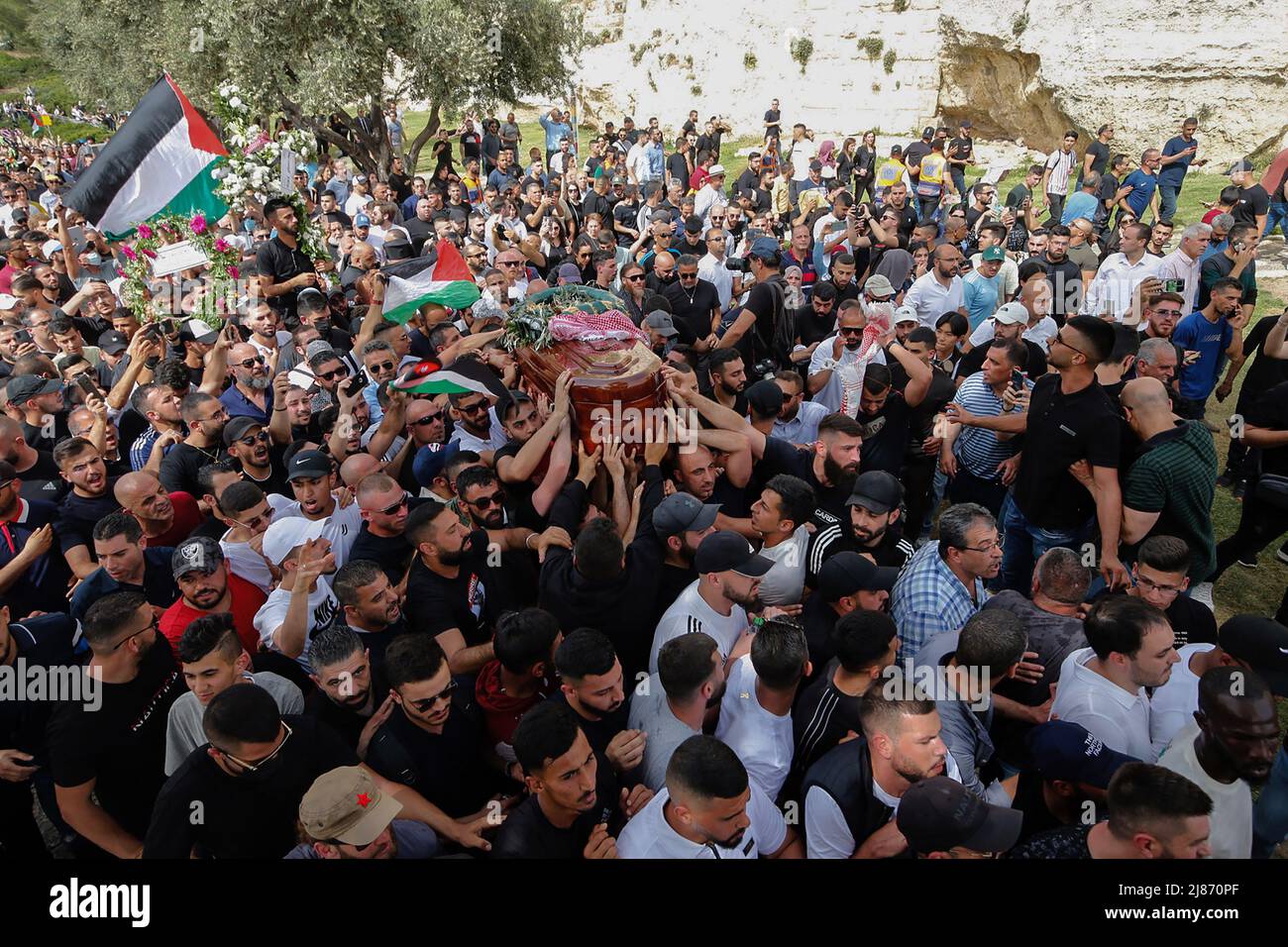 Jerusalem, Middle East. 13th May, 2022. Palestinian wave national flags as they carry the casket of slain Al-Jazeera journalist Shireen Abu Aklel during her funeral procession from the church toward the cemetery, in Jerusalem, Israel on Friday, May 13, 2022. Abu Akleh was shot on May 11th while covering a raid in the Israeli-occupied West Bank. Photo by Jamal Awad/UPI Credit: UPI/Alamy Live News Stock Photo