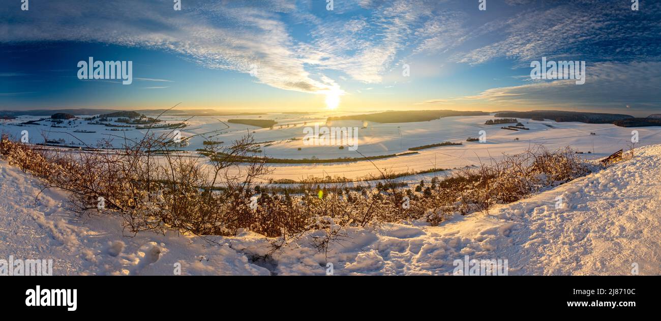 Panorama shot of scenic sunset over snowy winter landscape in the Swabian Alps in Southern Germany Stock Photo