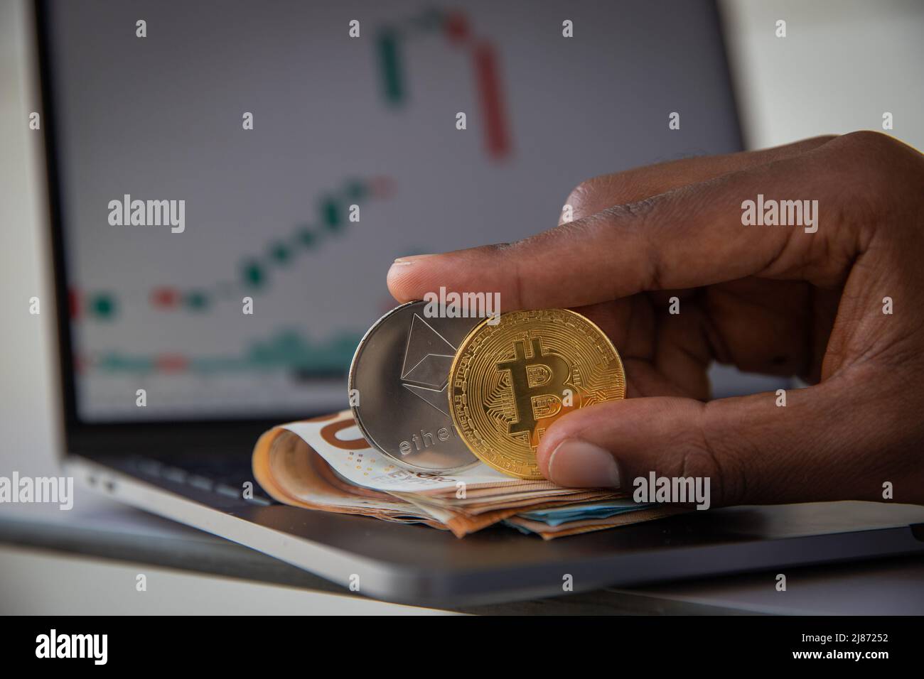 Close-up of two Bitcoin and Ethereum coins with euro banknotes and charts, trading profit concept Stock Photo