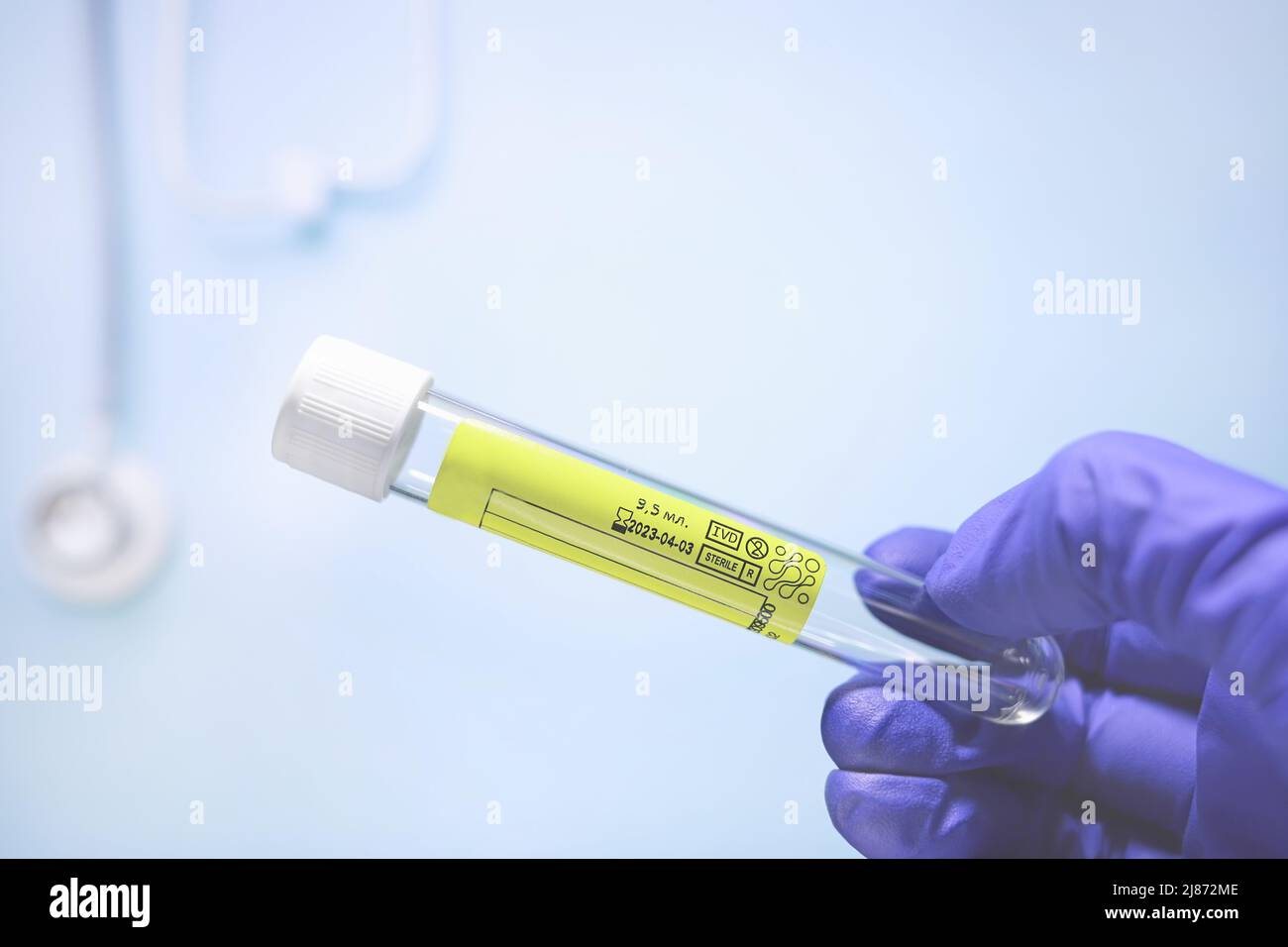 Testtube for taking urine in a doctor's hand in medical glove on blue