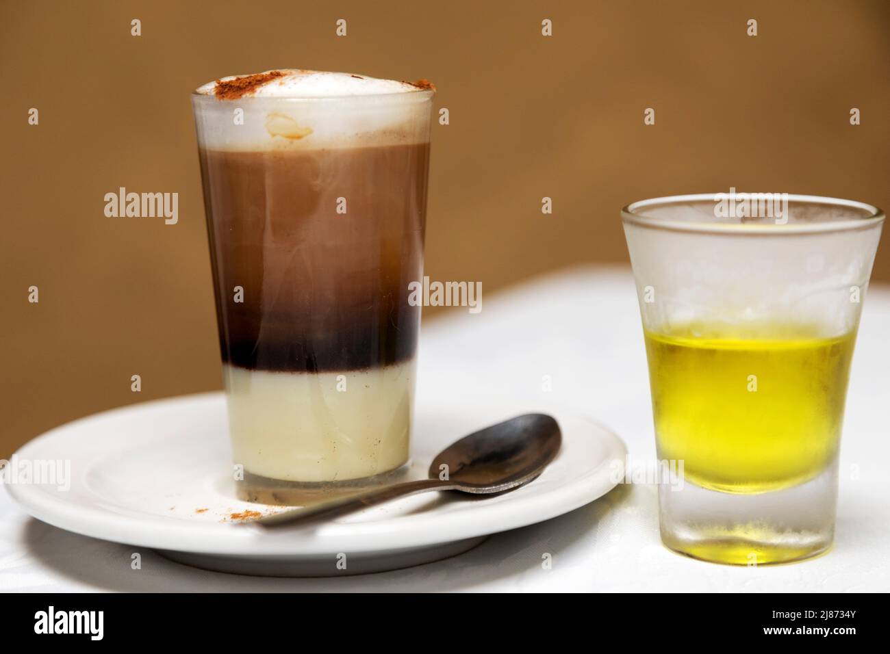 A traditional Barraquito coffee and glass of liqueur served in Tenerife, Spain. The style of coffee is popular across the Canary Islands and features Stock Photo