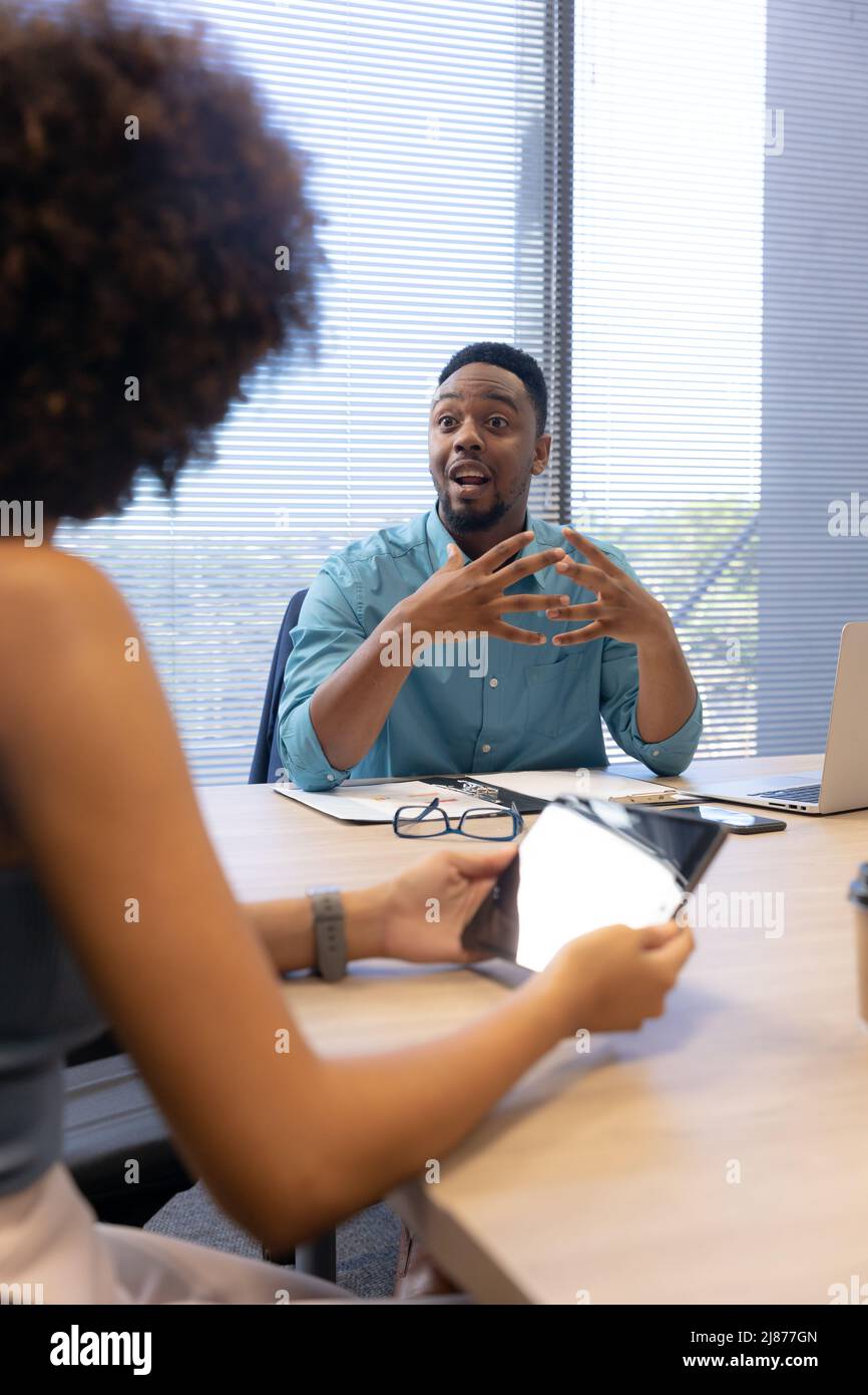 Confident african american businessman gesturing while discussing with hispanic businesswoman Stock Photo