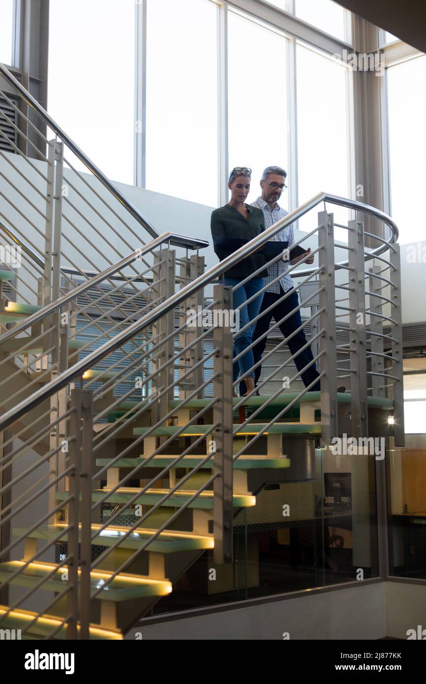 Low angle view of cauacsian colleagues planning while moving down on staircase at modern workplace Stock Photo