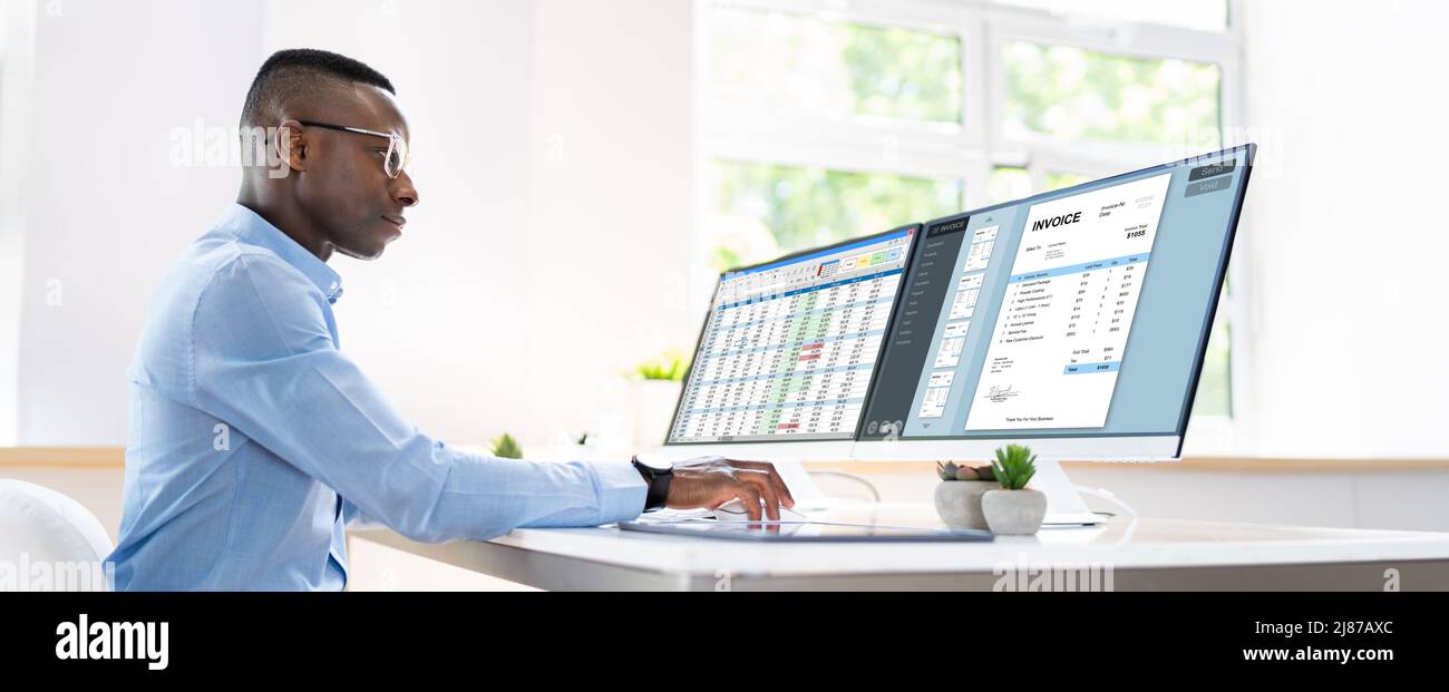 Businessperson Analyzing Invoice On Computer In Office Stock Photo