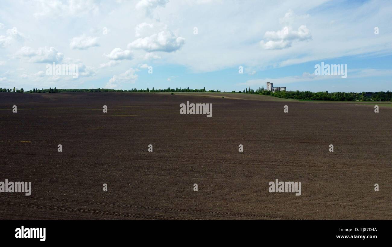 Aerial drone view flight over huge plowed field and blue sky. Skyline, horizon Stock Photo