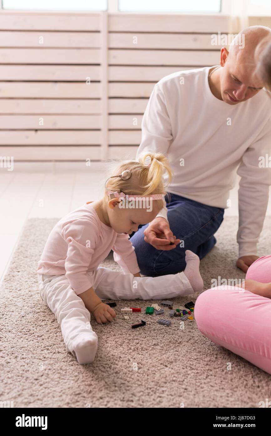 Happy child girl with cochlear implant having fun with her father - hearing aid for deaf and innovative health technology concept Stock Photo