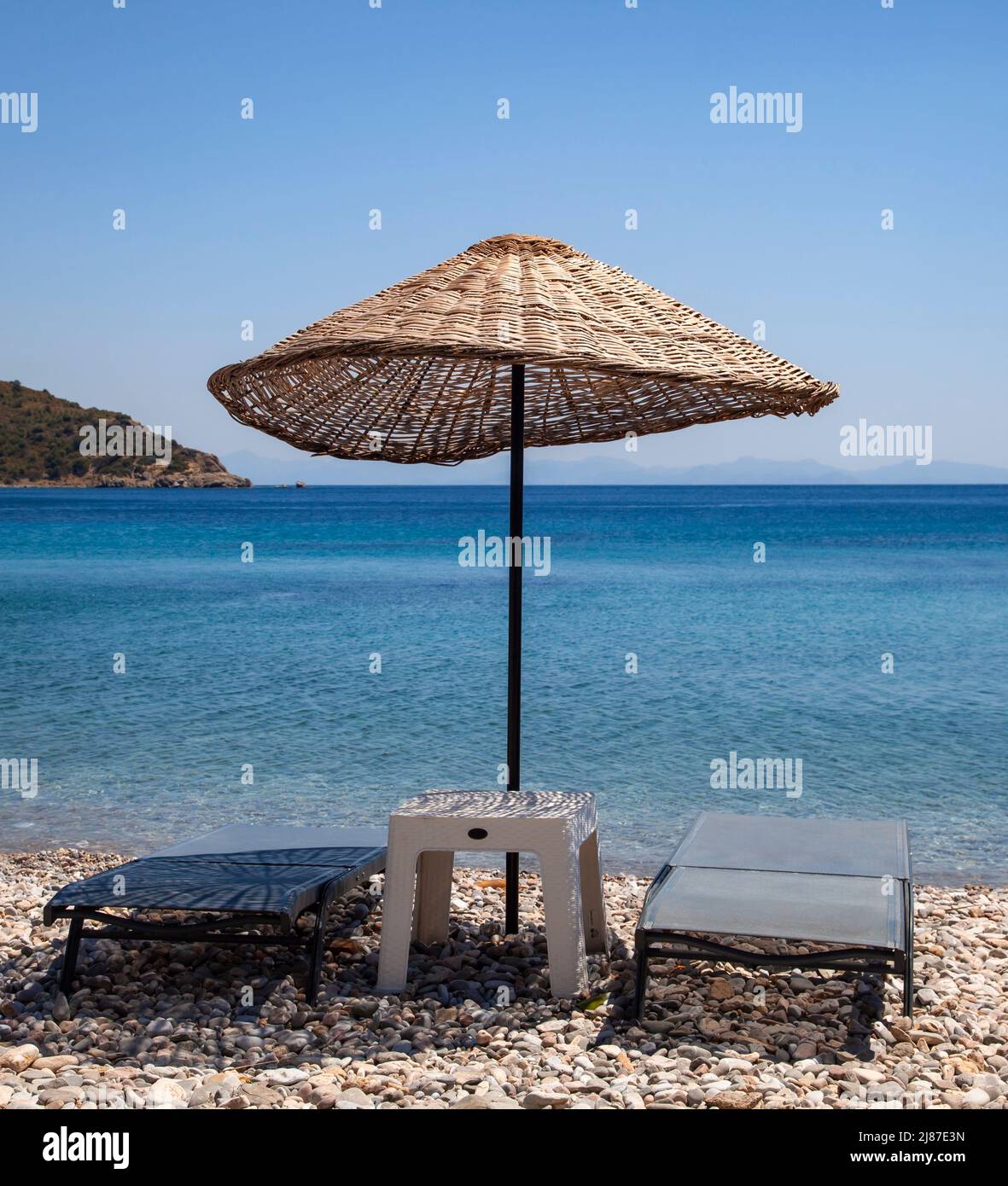 Wicker sunshade parasol and two empty sun loungers on the beach. Holiday concept. Landscape. Stock Photo